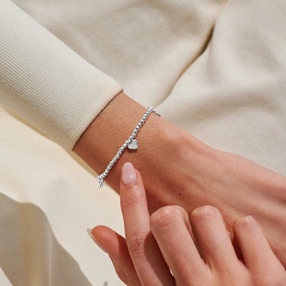 Model wearing silver beaded stretch bracelet with heart charm