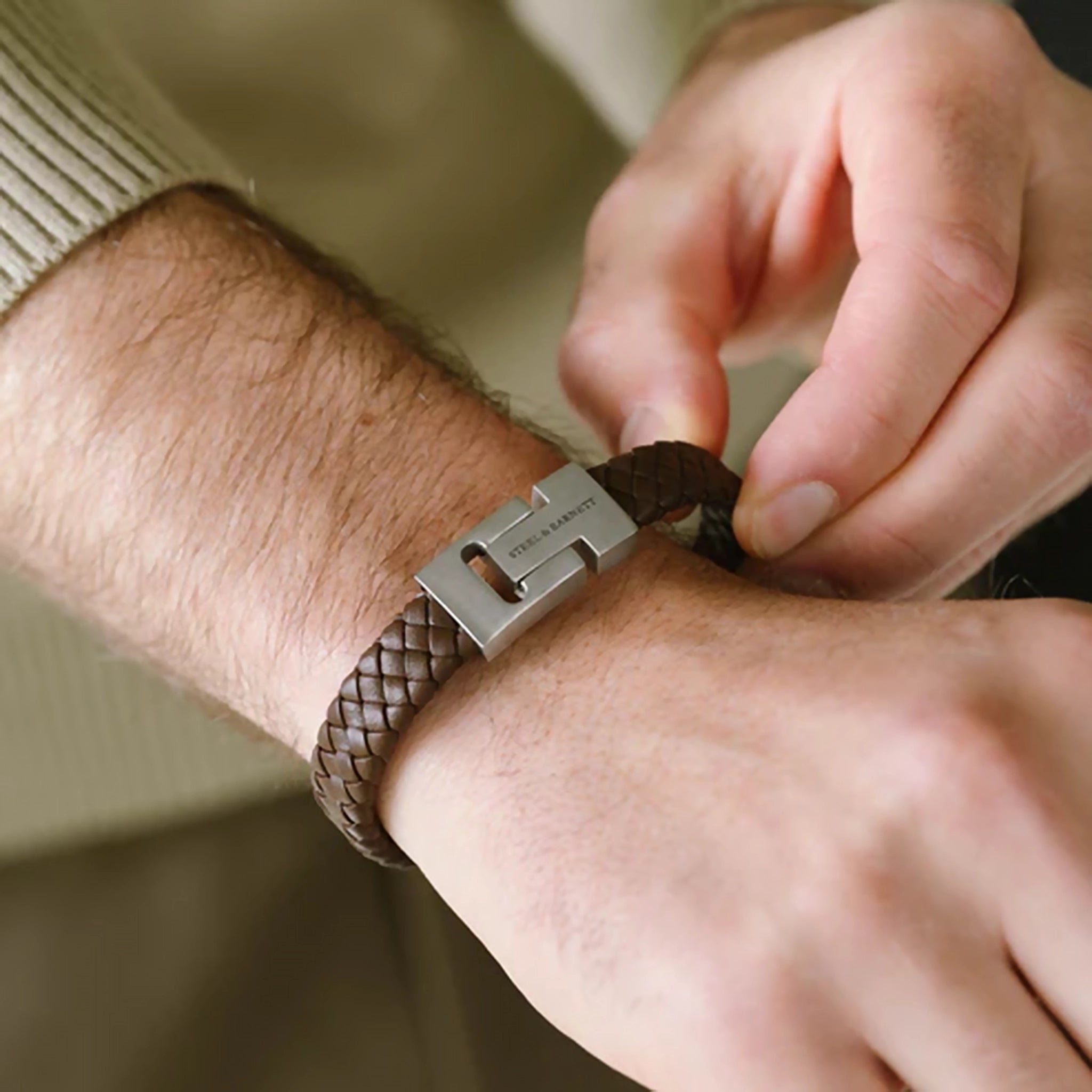 Model wearing braided brown leather bracelet with stainless steel bar detail and chunky slider clasp