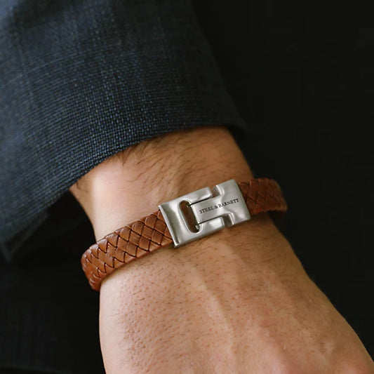 Model wearing braided brown leather bracelet with stainless steel bar detail and chunky slider clasp