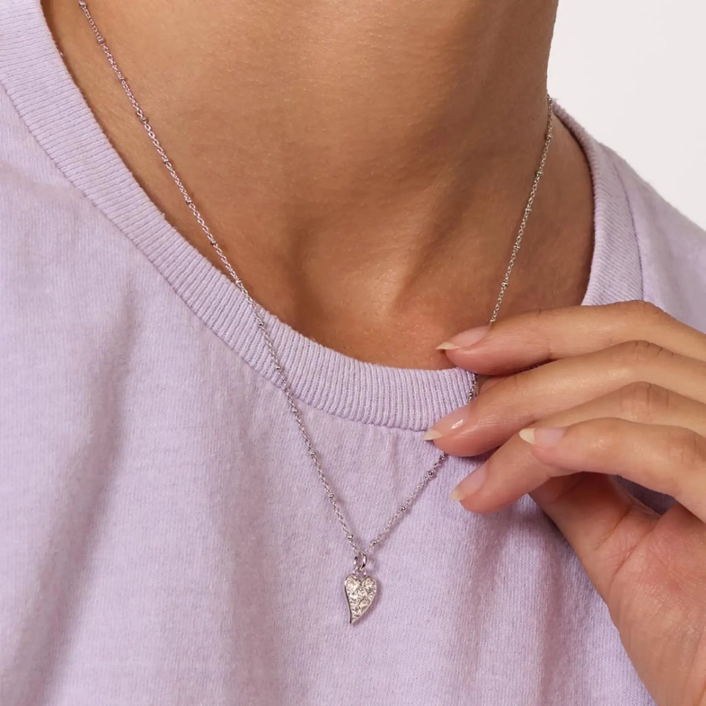 Asymmetrical heart shaped pendant with white topaz stones and silver ball chain on model