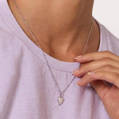 Asymmetrical heart shaped pendant with white topaz stones and silver ball chain on model