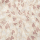 Detailed zoom of a scarf featuring a beige background with white and pink heart pattern and a short fringe