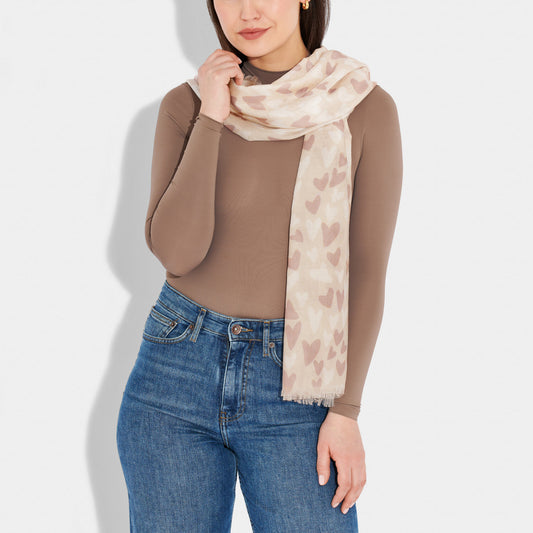 Model wearing a scarf featuring a beige background with white and pink heart pattern and a short fringe
