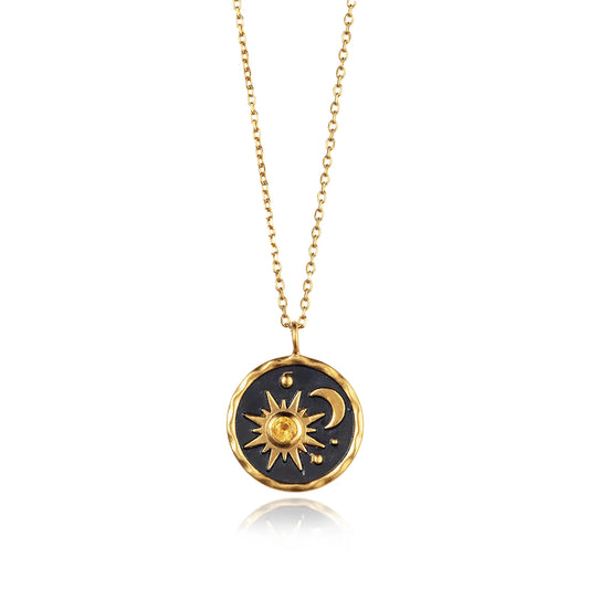 Gold coin shaped necklace with black centre and a sun and moon motif set with an orange citrine stone