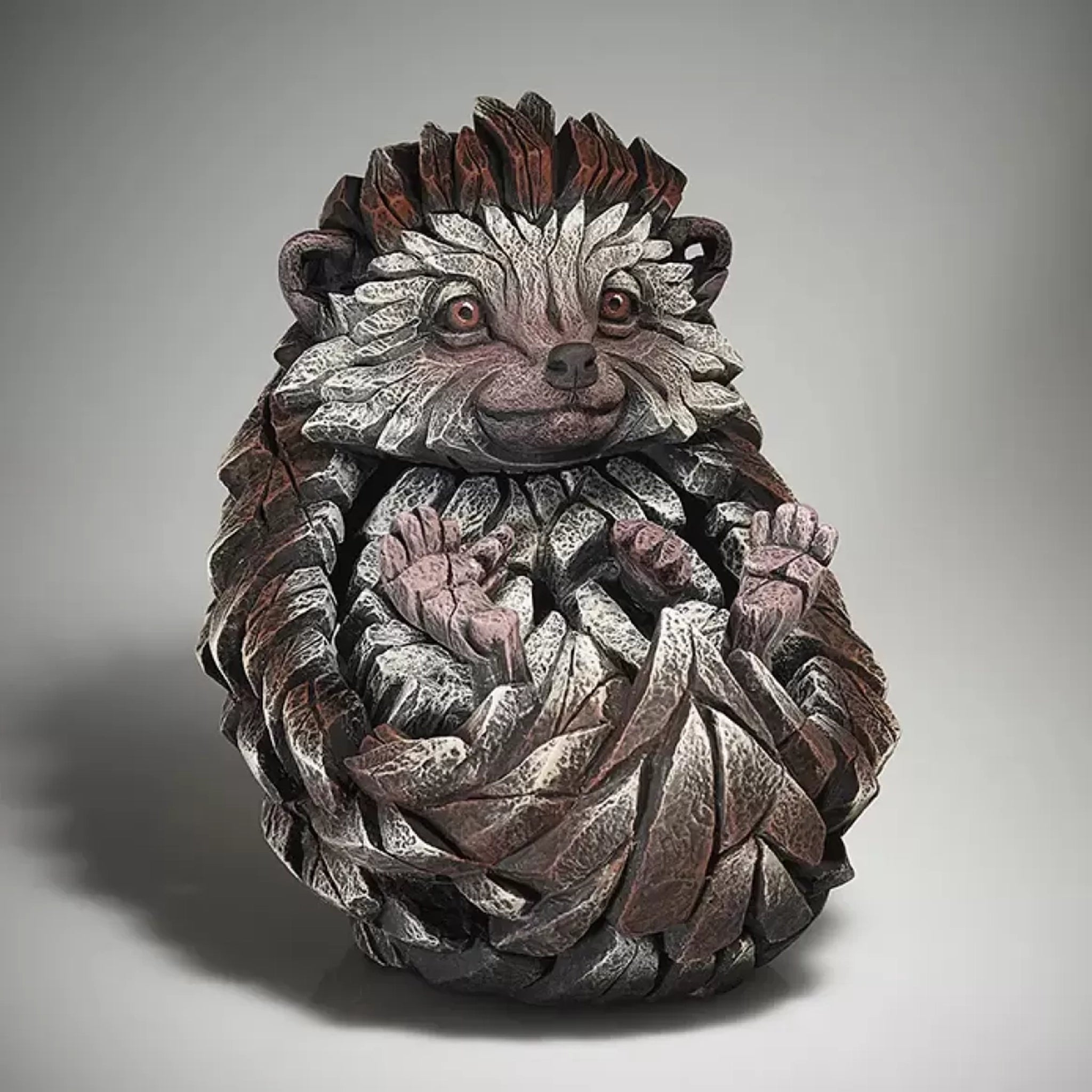 A textured and painted curled sitting hedgehog sculpture side view