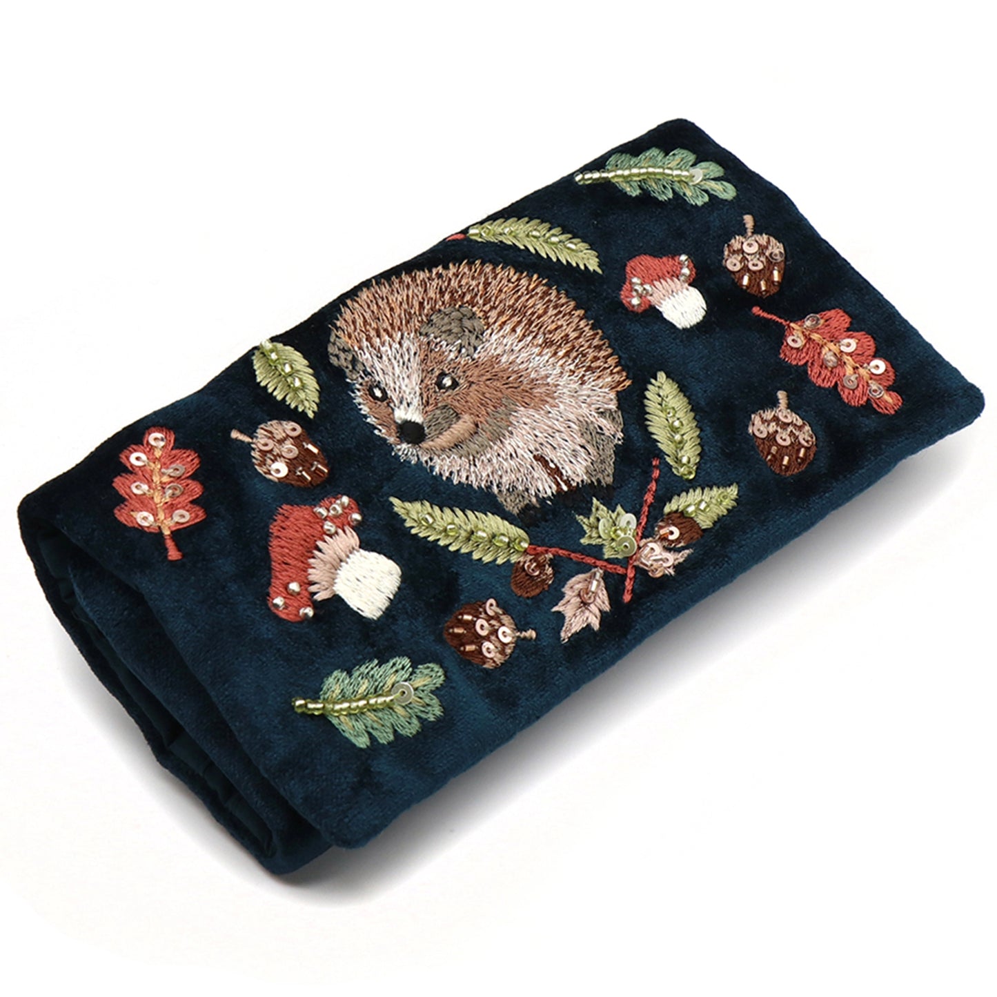 A dark teal velvet jewellery roll with an embroidered and beaded hedgehog design
