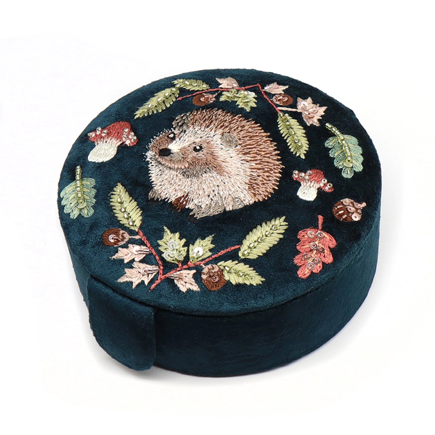 A round dark teal velvet jewellery box with an embroidered and beaded hedgehog design
