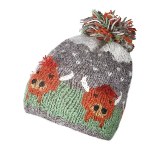 A knitted hat featuring Highland cows and a large pompom