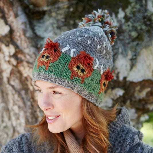 Model wearing a knitted hat featuring Highland cows and a large pompom