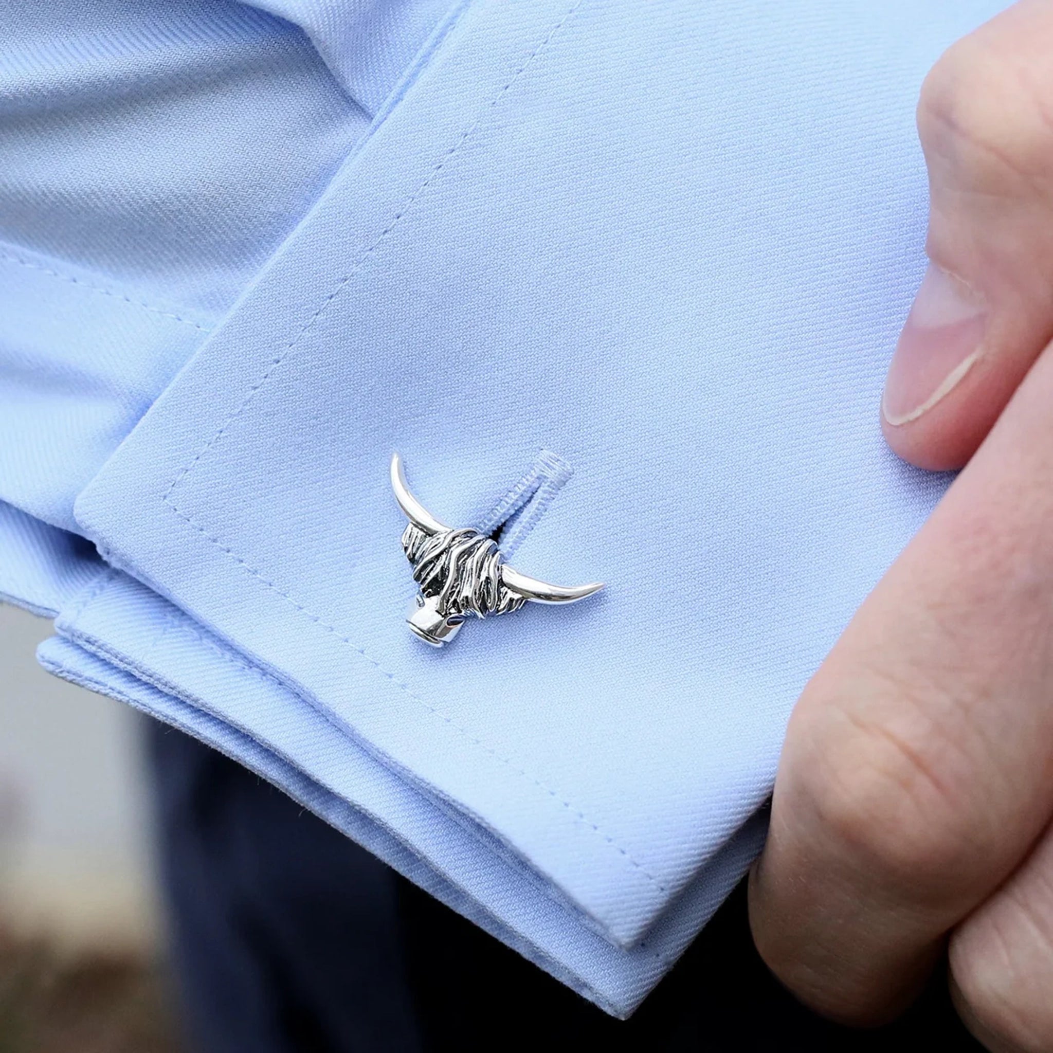 A pair of silver cufflinks shaped like Highland cow heads with simple T-bar clasps and oxidised details on cuff