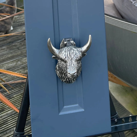 A silvery gunmetal coloured Highland cow shaped door knocker