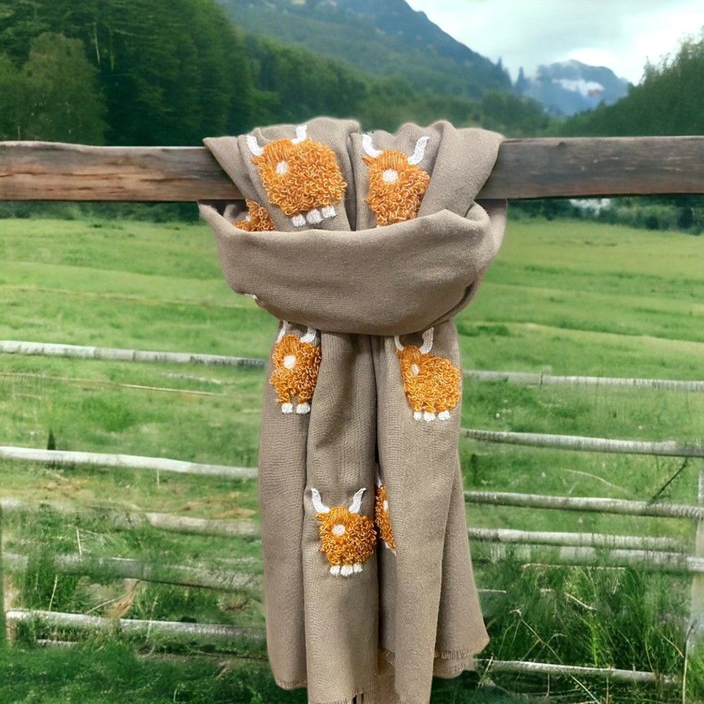 A beige coloured scarf with embroidered fluffy Highland cows