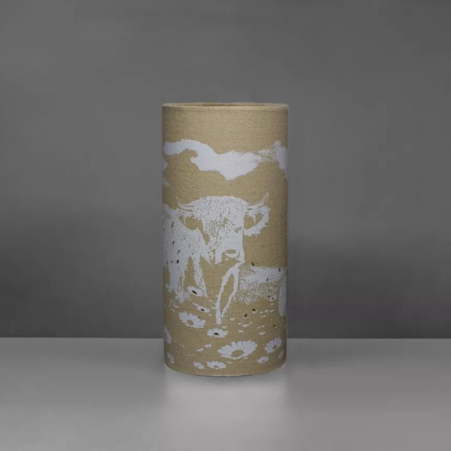 A linen look fabric table lamp with a Highland cow design and cut out details