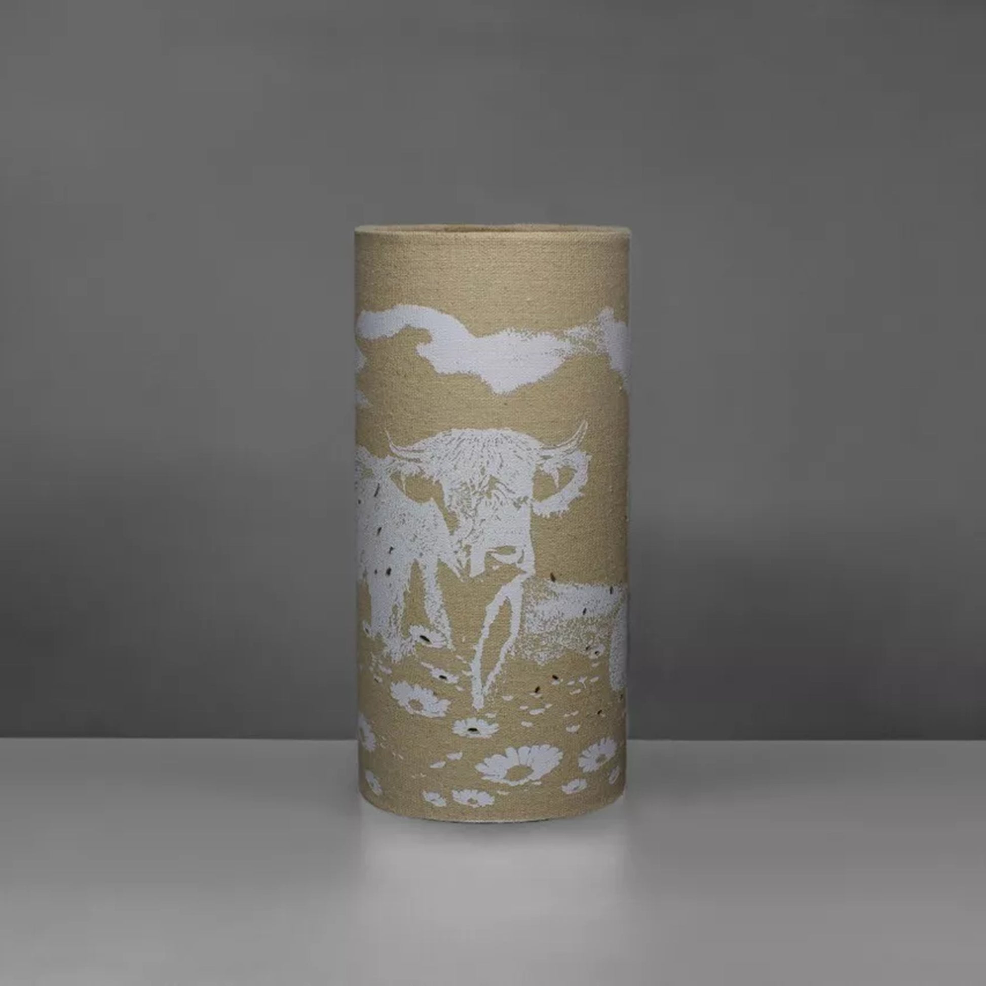 A linen look fabric table lamp with a Highland cow design and cut out details