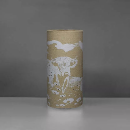 A linen look fabric table lamp with a Highland cow design and cut out details