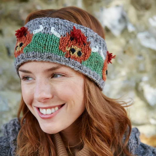 Model wearing a knitted headband in grey featuring a row of Highland Cows