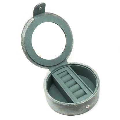 A round seafoam green velvet jewellery box with two open compartments and a ring roll