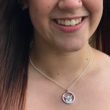 Model wearing a necklace with a pendant featuring a Highland cow in a round frame