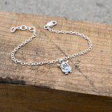 A silver bracelet featuring a chain with a little Highland cow charm