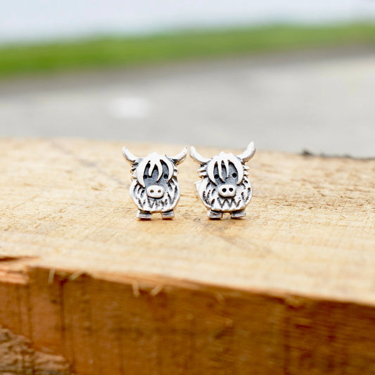 A pair of silver stud earrings shaped like Highland cows