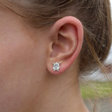 Model wearing a pair of silver stud earrings shaped like Highland cows