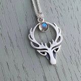 A silver pendant with a Celtic style stag head and a round labradorite stone on a silver chain