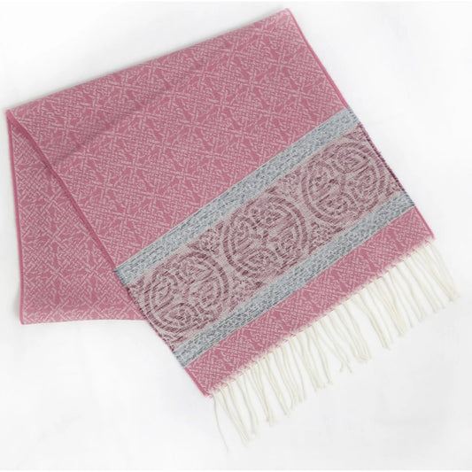 A soft pink scarf with celtic knot designs and a complimenting border with darker pink and blue and a white tassel trim