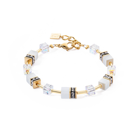 A gold steel bracelet with white cube beads and stones