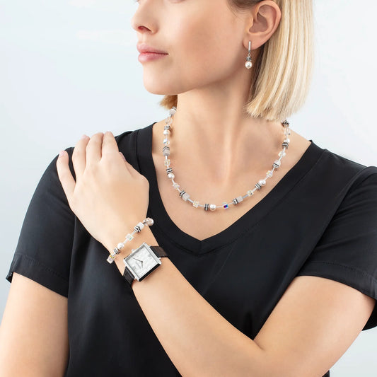 Model wearing a pair of drop earrings featuring pearls and rhinestones