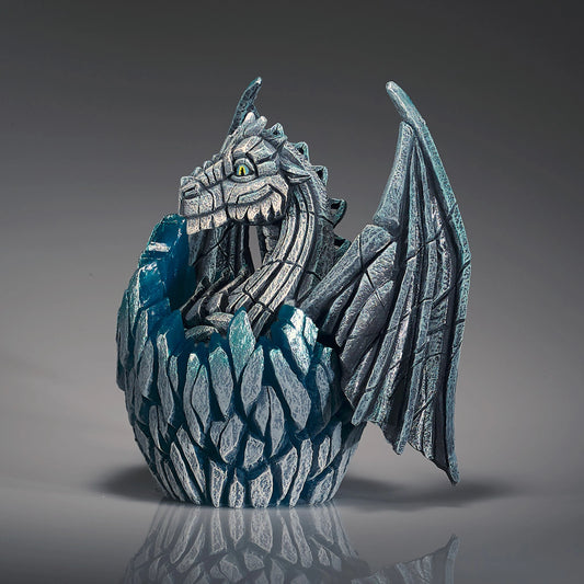 Side view of a modern sculpture of a white baby dragon hatching from an egg