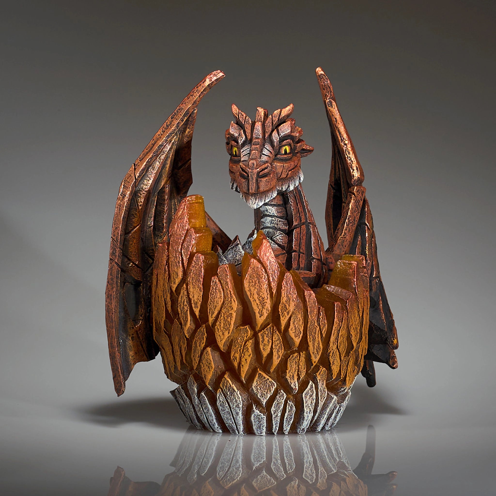 A modern sculpture of a baby dragon hatching from an egg 