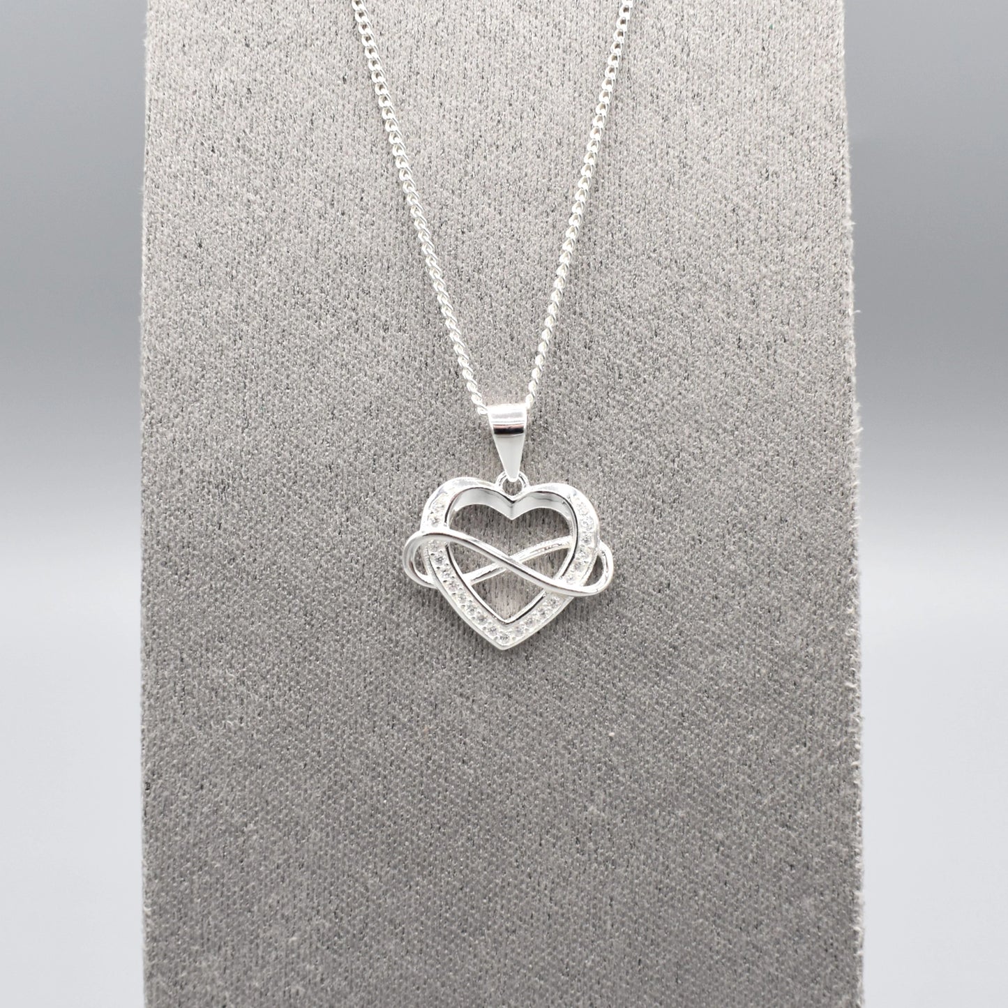 Silver pendant with infinity sign interlocking an open heart set with CZ stones