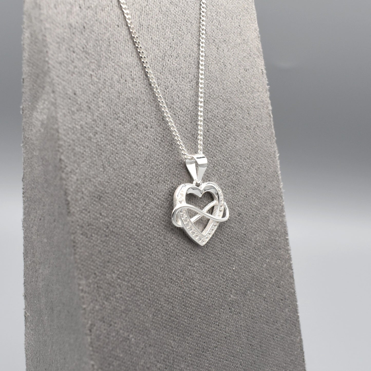 Silver pendant with infinity sign interlocking an open heart set with CZ stones side view