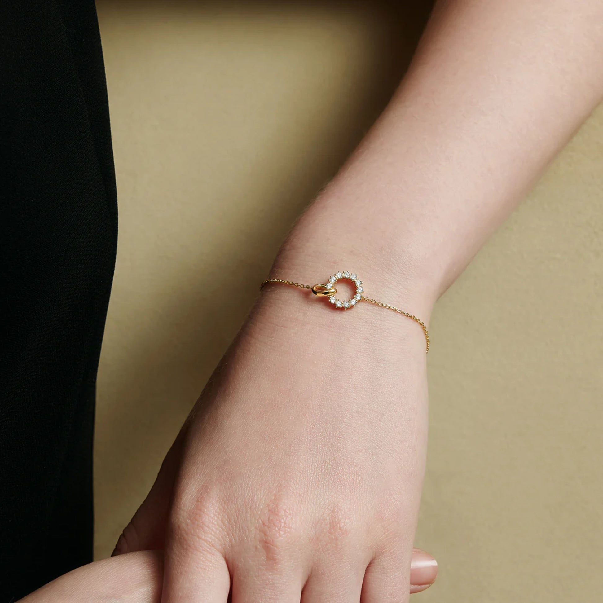 Model wearing interlinked circle gold chain bracelet with CZ stones