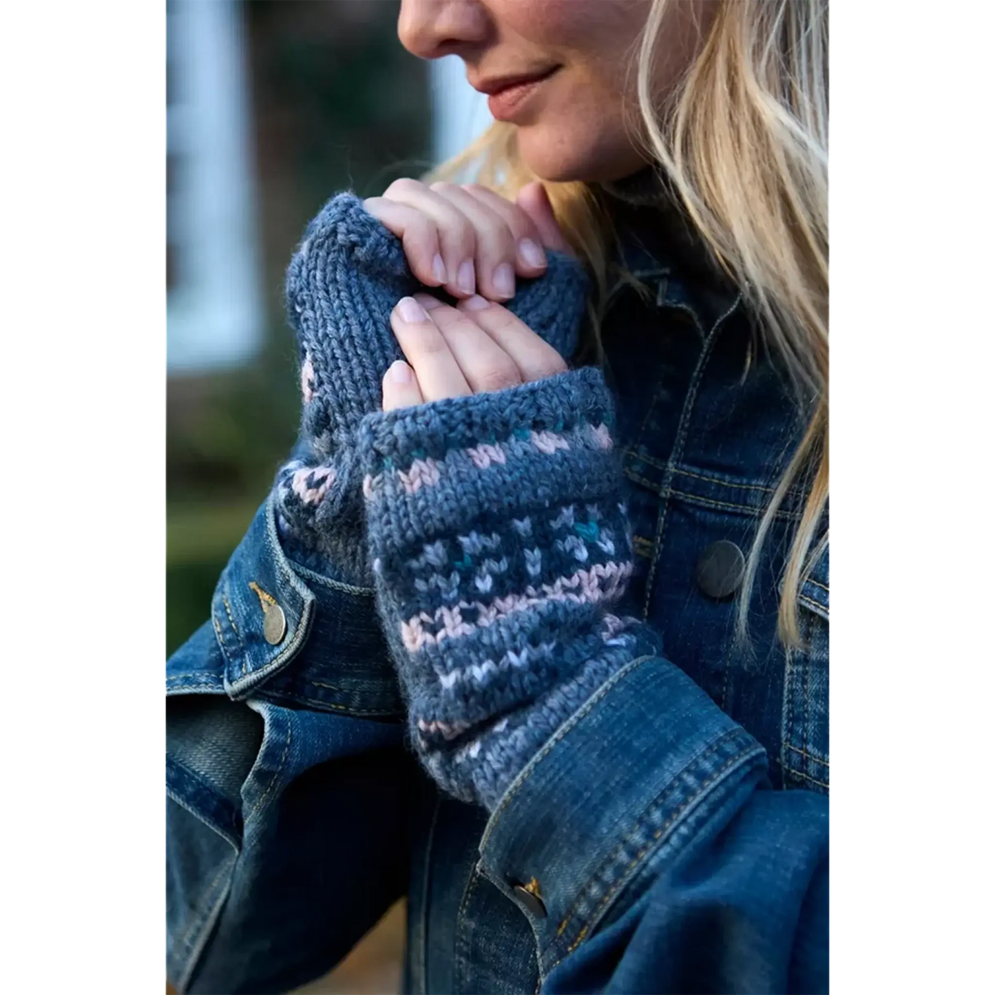 Model wearing a knitted fair isle handwarmer with blue and pink stripes