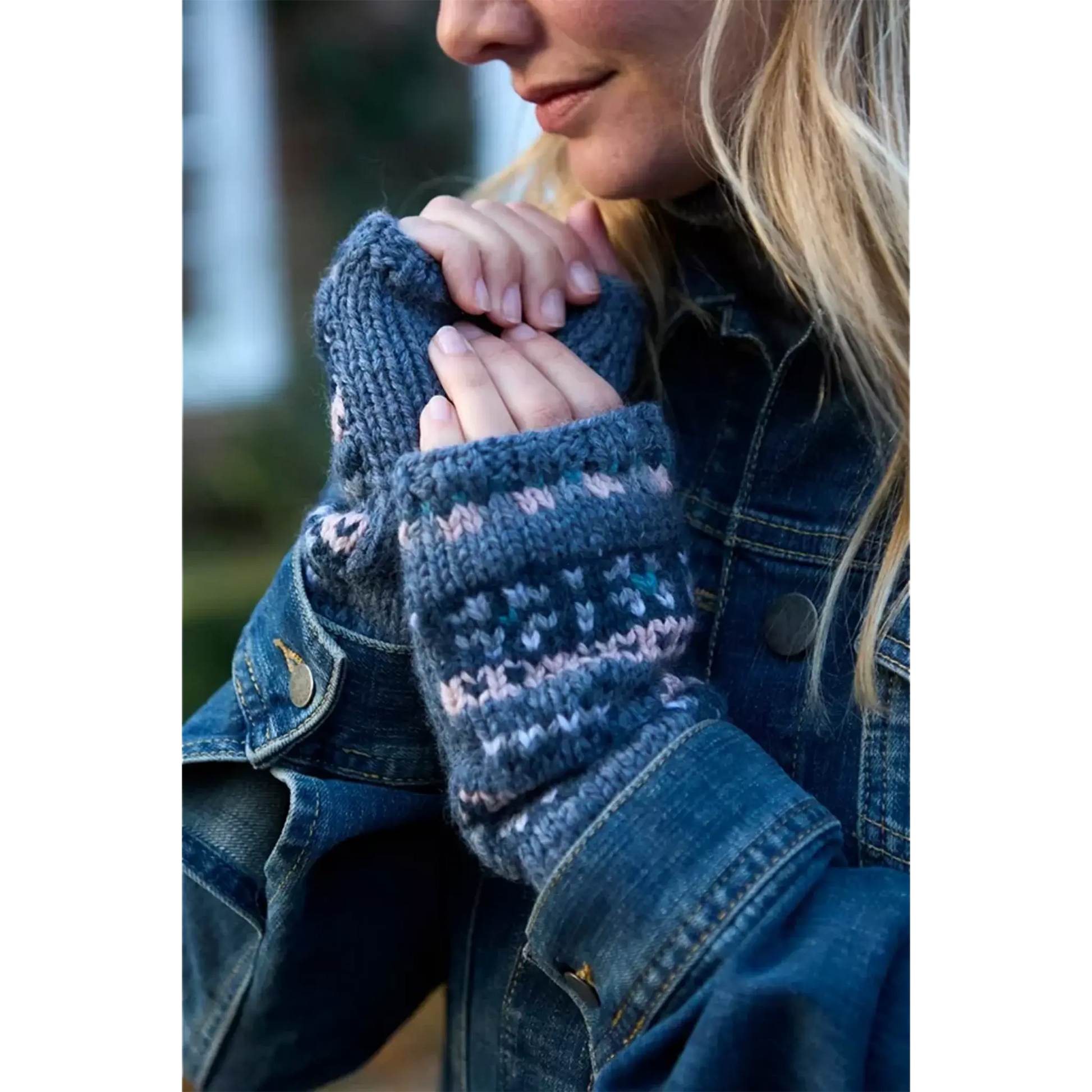 Model wearing a knitted fair isle handwarmer with blue and pink stripes