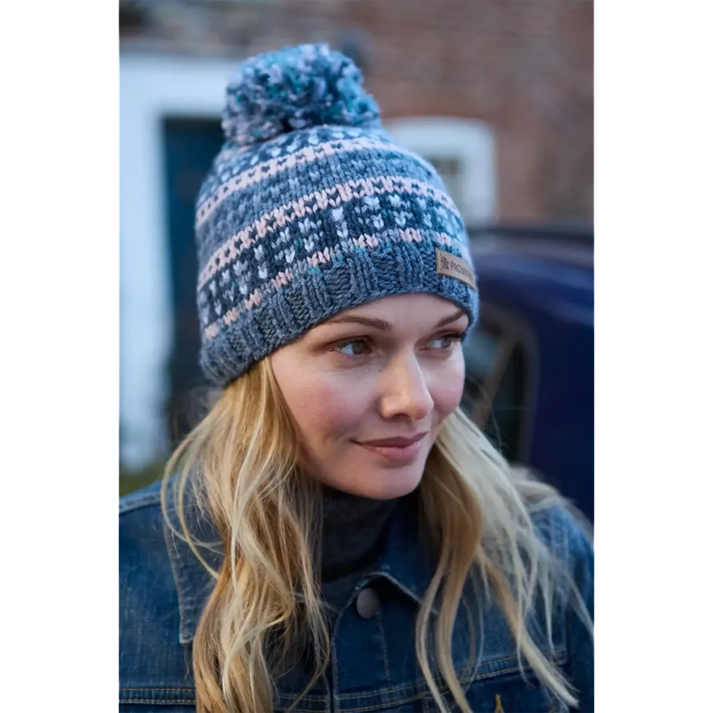 Model wearing a knitted bobble hat with blue and pink stripes