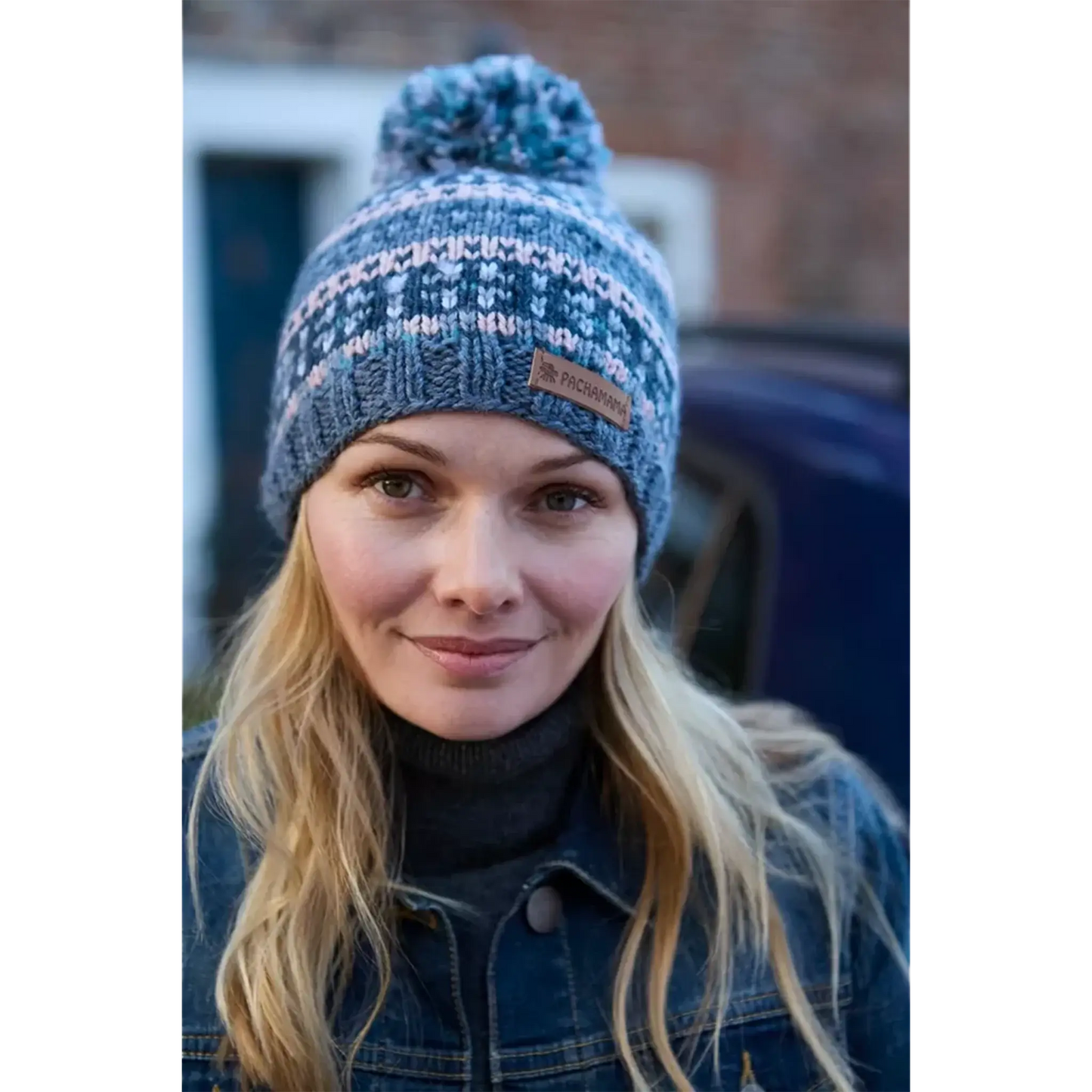 Model wearing a knitted bobble hat with blue and pink stripes