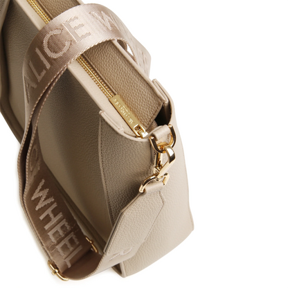 Stone crossbody bag with canvas strap featuring the Alice Wheeler logo in a repeat pattern and gold zip