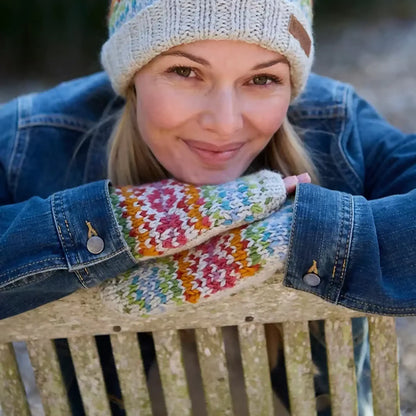 Model wearing knitted oatmeal handwarmers with rainbow chevron heart fair isle pattern