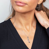 Model wearing a simple polished silver long triple heart shaped pendant