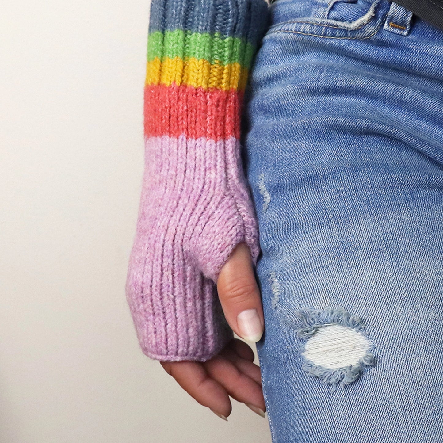 Model wearing lilac purple fingerless gloves with ribbed rainbow striped cuffs 