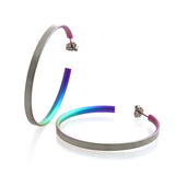 A pair of large open back hoop earrings with a matte titanium side and a rainbow inside