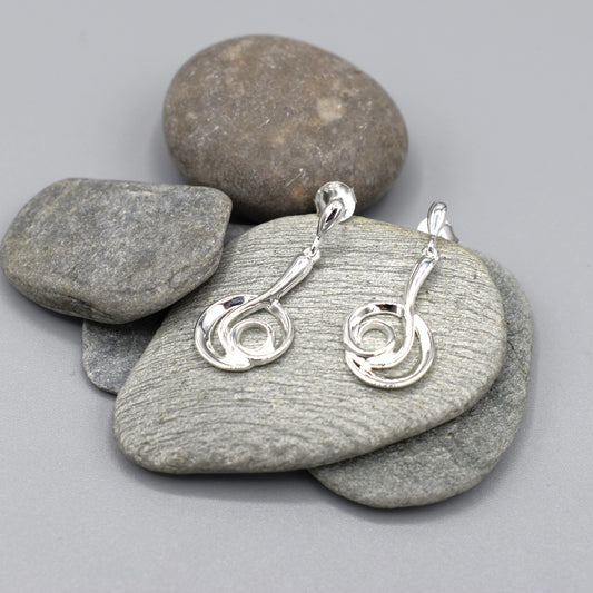 Silver earrings with modern design of a large coiled snake like swirl with polished texture