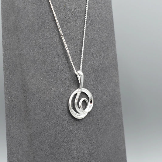 Silver pendant with modern design of a large coiled snake like swirl with polished texture