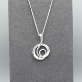 Silver pendant with modern design of a large coiled snake like swirl with polished texture