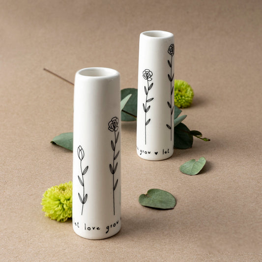 A white ceramic bud vase that says 'Let love grow' with floral pattern lifestyle