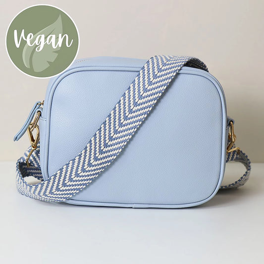 Light blue vegan leather cross body camera bag with white and grey simple chevron print woven strap