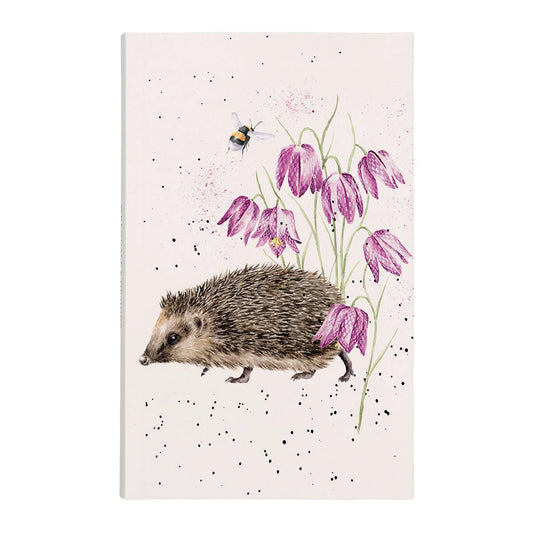 A pink notebook with a hedgehog strolling through pink flowers on the cover