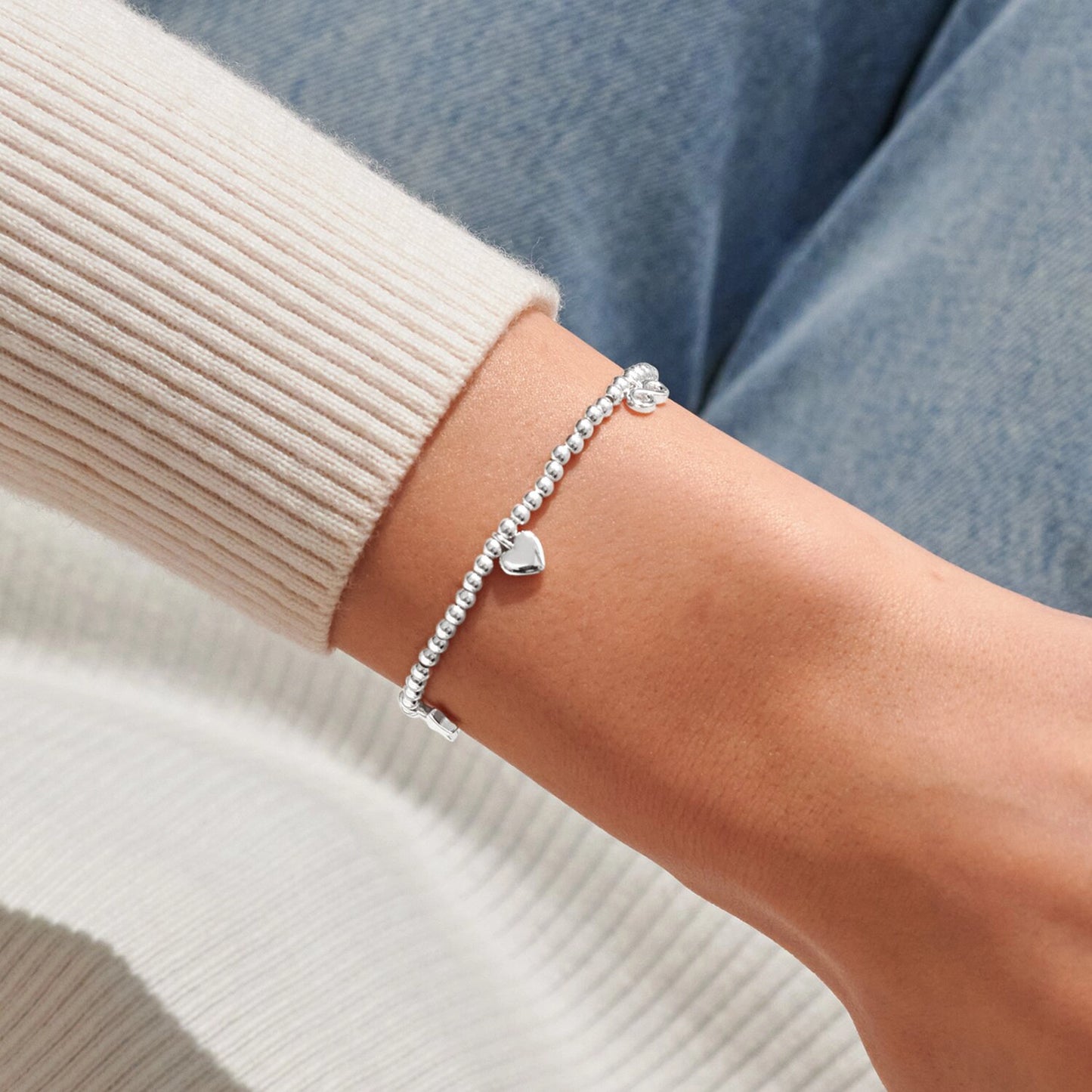 Model wearing silver stretch beaded bracelet with heart charm